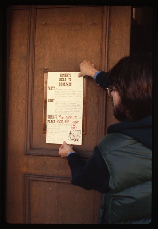 Man hanging a tenants' rights meeting poster